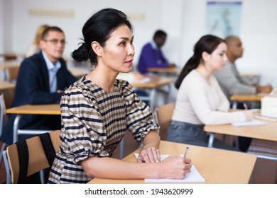 Concentrated Asian Woman Listening To Lecture In Classroom With Group Of Adult People. Postgraduate Education Concept..