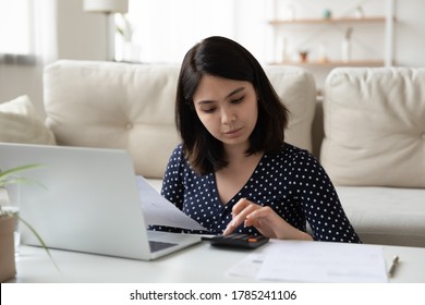 Concentrated Asian Young Woman Work On Laptop Mange Household Finances Expenditures. Focused Vietnamese Millennial Use Computer, Calculate Home Utility Expenses. Female Pay Bills Taxes Online