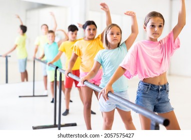 Concentrated Assiduous Preteen Girl Working Near Ballet Barre During Group Choreography Class .