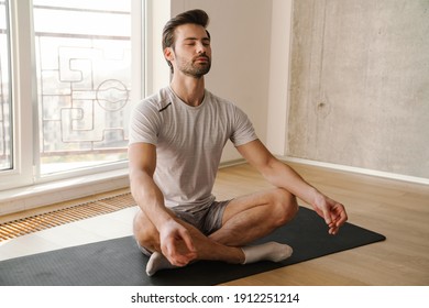 Concentrated athletic man meditating after workout at home