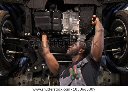 concentrated auto mechanic man repairing car hood alone, using tools