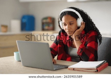 Concentrated black student at home e-learning with laptop and headphone