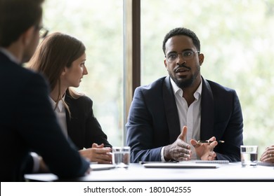 Concentrated Black Team Leader Posing Problem To Employees, Afro-american Coach Or Mentor Setting Target To Group Of Trainees, Manager Discussing His Business Idea With Diverse Colleagues On Meeting