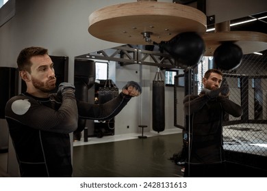 Concentrated boxer honing skills on speed bag in boxing gym - Powered by Shutterstock