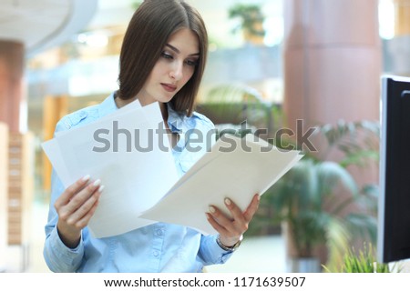 Concentrated business lady comparing documents at office.