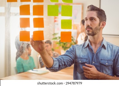 Concentrated Businessman Looking Post Its On The Wall In The Office