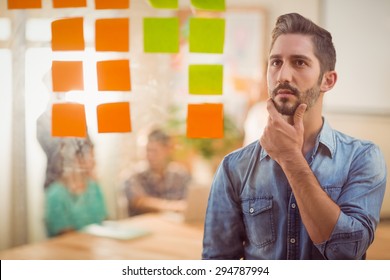 Concentrated Businessman Looking Post Its On The Wall In The Office