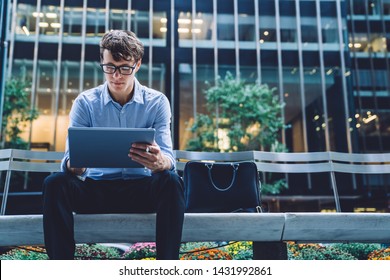 Concentrated Businessman Reading Received Email On Modern Tablet While Sitting Outdoors Front Office Building, Caucasian Male Proud Ceo In Eyewear Checking Message On Digital Touch Pad In Downtown