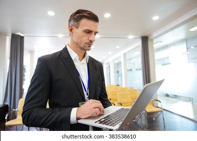 Concentrated businessman working with laptop in empty conference room - Powered by Shutterstock