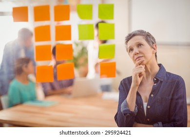 Concentrated Businesswoman Looking Post Its On The Wall In The Office