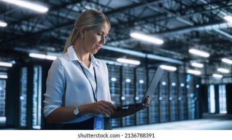 Concentrated Businesswoman or Manager Using Laptop Computer, While Standing in Dark Office or Hall and Working on Financial, Business and Marketing Projects. Business Concept - Powered by Shutterstock