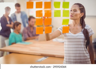 Concentrated Businesswoman Pointing Post Its On The Wall In The Office