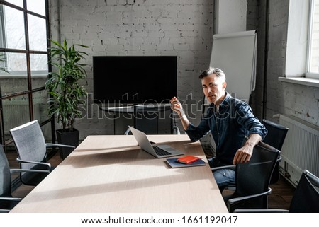 Concentrated busy adult man boss work in office meeting room alone, on his personal account. Successful business strategy plan concept. Confident office worker indoor, coworking. People lifestyle