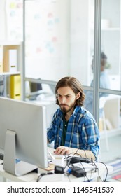 Concentrated Busy Young IT Specialist With Beard And Mustache Focusing On Computer Problem And Attentively Examining Data On Computer In Office