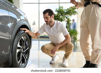 Concentrated car dealership client checking tyre quality - Powered by Shutterstock