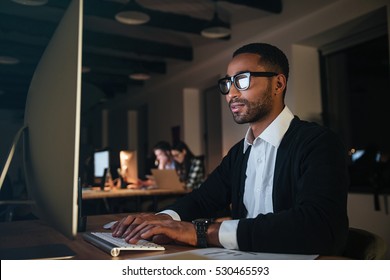 Concentrated Dark Skinned Businessman Working Late At Night In Office With Computer.