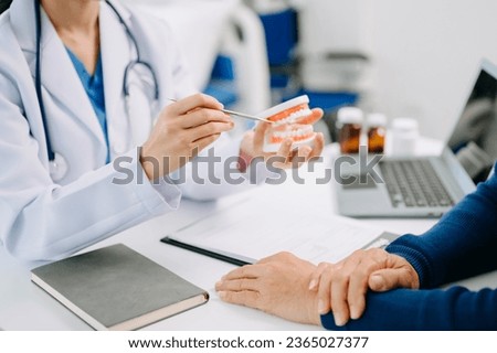 Concentrated dentist sitting at table with jaw samples tooth model and working with tablet and laptop in dental office professional dental clinic. medical doctor working  ストックフォト © 