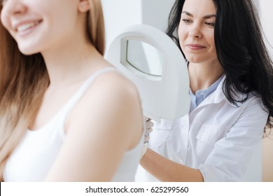 Concentrated dermatologist using medical loupe in the clinic - Powered by Shutterstock