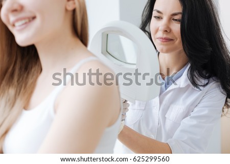 Concentrated dermatologist using medical loupe in the clinic
