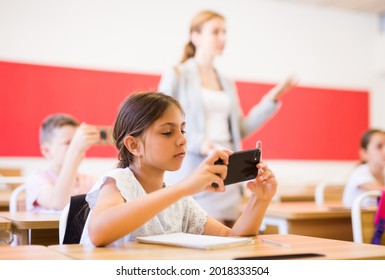 Concentrated Diligent Tween Girl Sitting At Lesson In Classroom, Using Mobile Phone ..