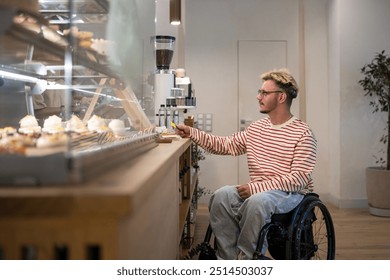 Concentrated disabled man in wheelchair paying for purchase in coffee shop using terminal, credit card. NFC technology, contactless payment, using bonus loyalty system, completing cashless transaction - Powered by Shutterstock