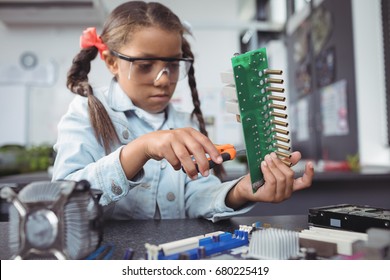 Concentrated elementary girl assembling circuit board on desk at electronics lab - Powered by Shutterstock