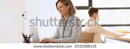 Concentrated employees work on computers sitting at tables in modern office. Woman and man do professional researches for future project