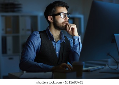 Concentrated Entrepreneur Or Manager Sitting By Desk In Front Of Computer Monitor While Working At Night