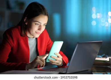 Concentrated Entrepreneur Using Mobile Phone And Laptop In The Night At Home