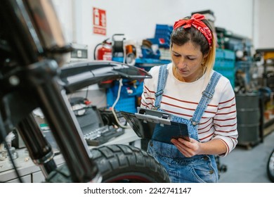 Concentrated female mechanic with clipboard reviewing information of motorcycle on garage - Powered by Shutterstock