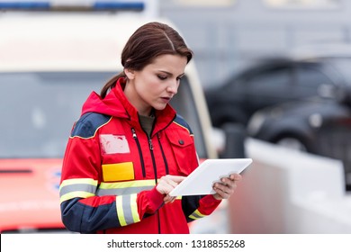 Concentrated Female Paramedic In Uniform Using Digital Tablet