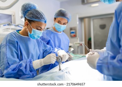 Concentrated Female Surgeon Performing Surgery With Her Team In Hospital Operating Room. Medics During Surgery In Operation Theater.