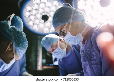 Concentrated Female Surgeon Performing Surgery With Her Team In Hospital Operating Room. Medics During Surgery In Operation Theater.