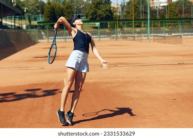 Concentrated female tennis player in motion during game, raining, playing tennis at open air court on sunny day. Concept of sport, hobby, active lifestyle, health, endurance and strength, ad - Powered by Shutterstock