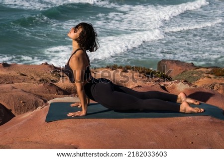 Concentrated fit woman making yoga exercises while laying on mat outdoors
