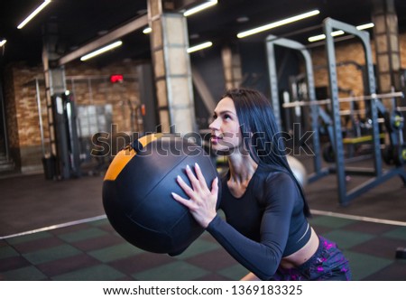Concentrated fit woman in sportswear doing exercise with med ball in gym