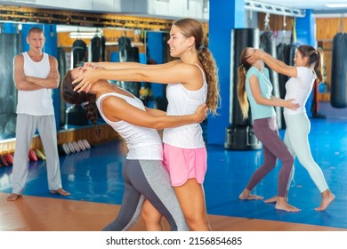 Concentrated girl using painful technique for eyes of female opponent during training at gym. Basic self-defense course for women..