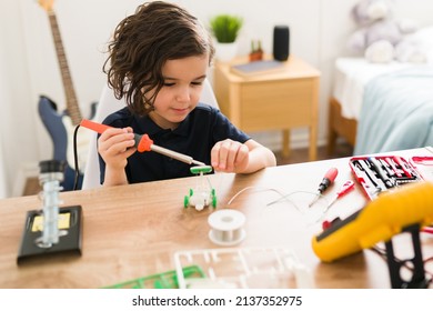 Concentrated Kid Using A Soldering Iron While Doing A Science Project To Become A Scientist When He Grows Up