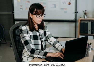 Concentrated Korean Female Employee Sitting Straight At Desk Is Working On The Laptop In A Bright Creative Office.