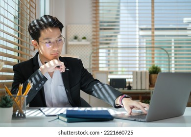 Concentrated Male Financial Advisor Using Laptop And Preparing Contract Document At Office Desk.	