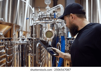 Concentrated man, technologist examining brewing equipment, maintaining thigh standards necessary for quality beer production. Concept of beer, brewery, manufacture, quality control - Powered by Shutterstock