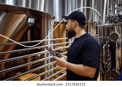 Concentrated man, technologist examining brewing equipment, maintaining thigh standards necessary for quality beer production. Concept of beer, brewery, manufacture, quality control - Powered by Shutterstock