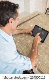 Concentrated man using digital table at home against night sky