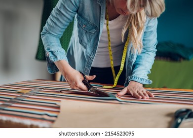 Concentrated Middle Aged Woman Tailor Cuts With Scissors Pattern Dress Detail On Sketch Lines For Sewing Machine. Workplace Of A Dressmaker. Handmade Concept.