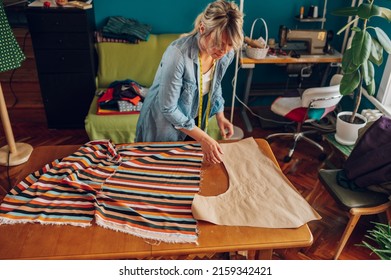 Concentrated Middle Aged Woman Tailor Making Pattern Dress Detail On Sketch Lines For Sewing Machine. Workplace Of A Dressmaker. Handmade Concept.