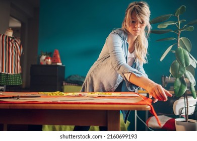 Concentrated Middle Aged Woman Tailor Using Pattern Dress Detail On Sketch Lines For Sewing Machine. Workplace Of A Dressmaker. Handmade Concept. Fashion Designer Working At Home.