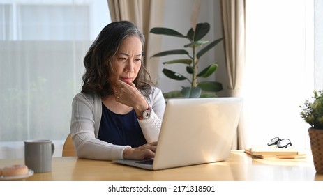 Concentrated Middle Aged Woman Watching Online Webinar, Working At Home With A Laptop Computer