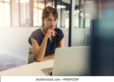 Concentrated Middle Aged Woman Working On Her Computer. Start-up Office Background