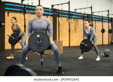 Concentrated middle-aged athletic man engaging in T-Bar row, targeting back muscles, in dynamic gym environment with fitness enthusiasts - Powered by Shutterstock