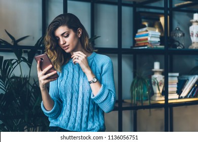 Concentrated millennial hipster girl installing application on cellular phone connected to wifi at campus, serious woman searching information and reading new in social networks using smartphone - Shutterstock ID 1136056751